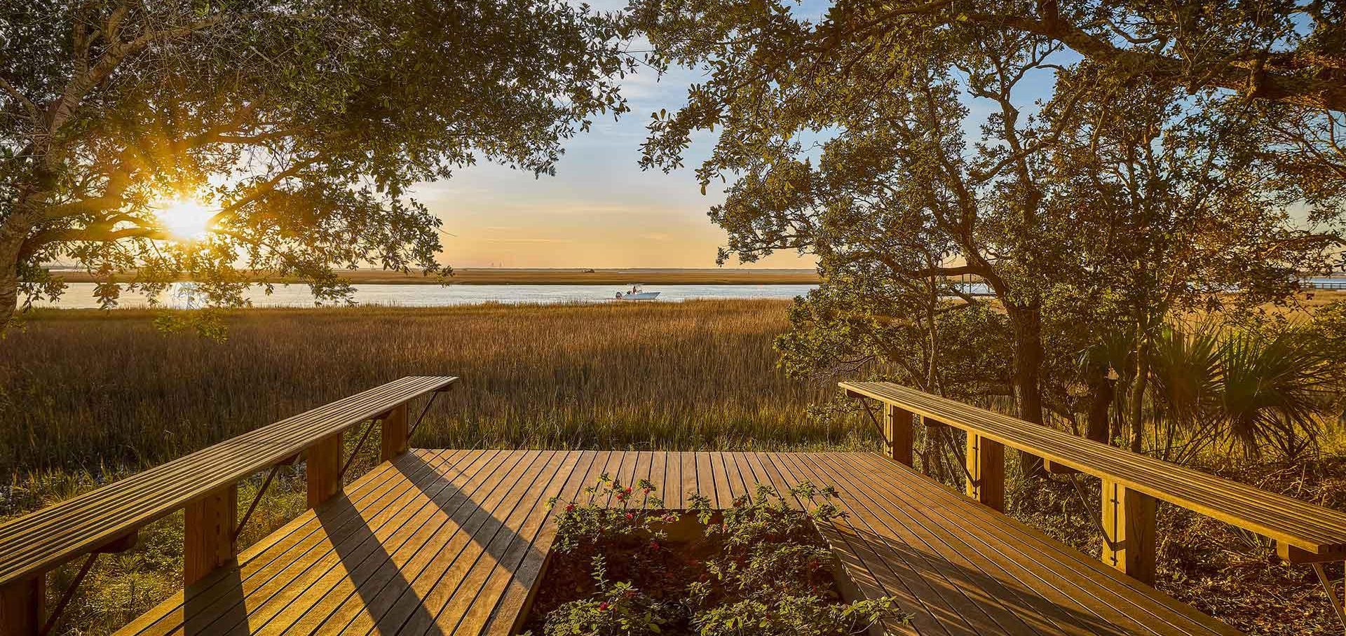 A wooden deck with benches and trees in the background.