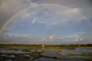 A rainbow over the water and some grass