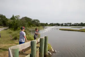 Two people standing on a fence near the water.