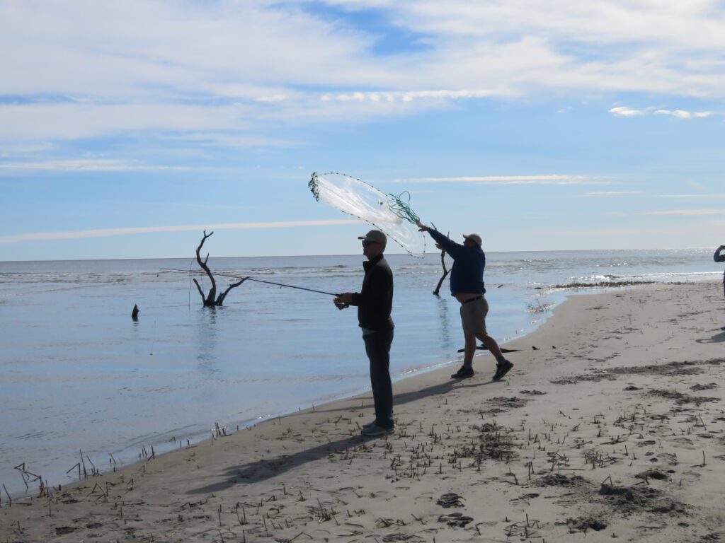 Men cast netting on the beach of Dewees Island